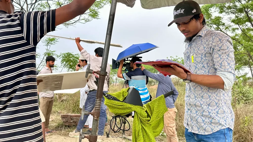 Faisal Khan Shuvo reviewing a script on an outdoor production location